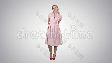 时尚笑脸的年轻美女模特在渐变背景下身着粉色连衣裙摆姿势的肖像。